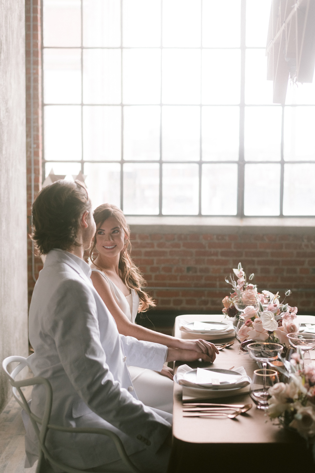 Bride smiling at the groom at the wedding table in a loft space