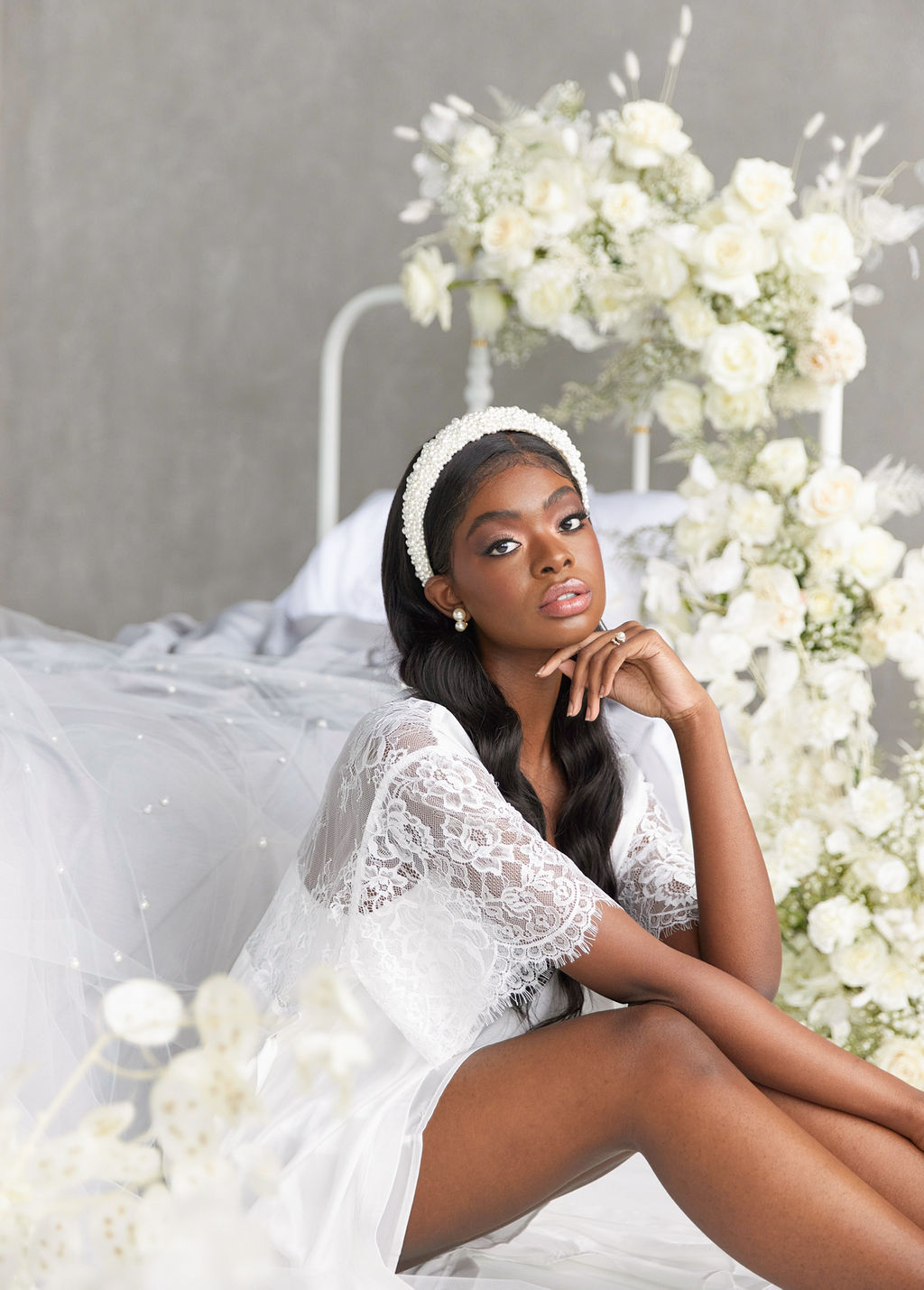a woman posing next to a wedding bed styled with roses