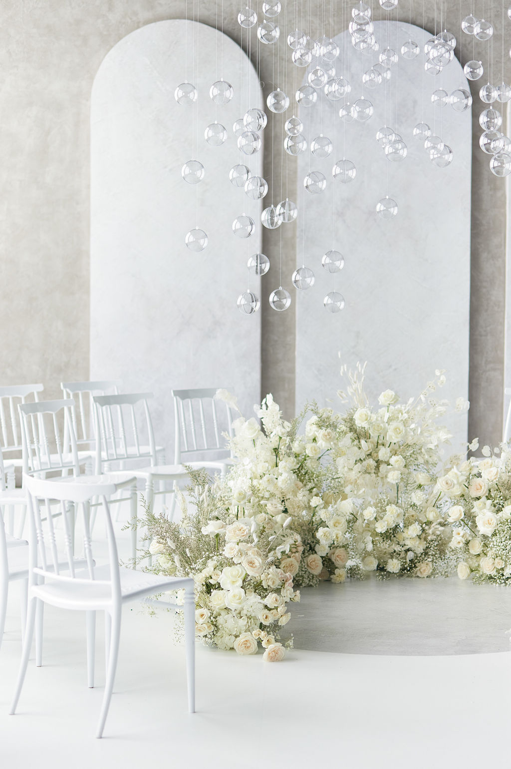 Wedding ceremony aisle decorated with flowers and white chairs