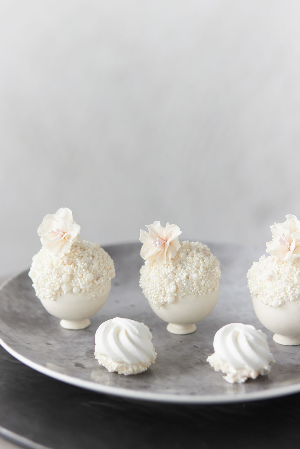White chocolate-covered round truffles decorated with white sprinkles and white chocolate flowers
